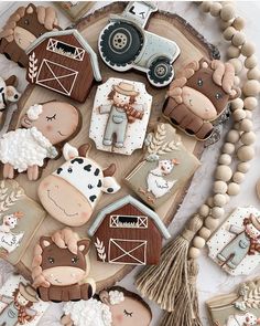 cookies decorated with farm animals and barn scenes on a wooden board surrounded by other decorations