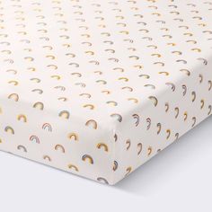 an image of a baby crib sheet with rainbows and clouds on it's side