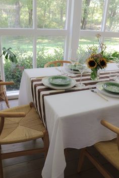 the table is set for two with sunflowers in vases and plates on them