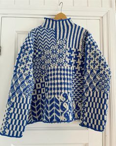 a blue and white knitted jacket hanging on a door handle, with the top half open