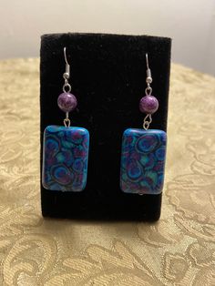 Made with a beautiful purple, blue and green peacock feather adorned rectangle bead. All wire is nickel free. Multicolor Square Beaded Jewelry, Blue Rectangular Earrings, Blue Rectangular Earrings With Ear Wire, Nickel-free Multicolor Rectangular Earrings, Bohemian Rectangular Earrings With Colorful Beads, Handmade Multicolor Rectangular Jewelry, Nickel Free Blue Rectangular Jewelry, Blue Rectangular Beaded Jewelry, Blue Beaded Rectangular Jewelry