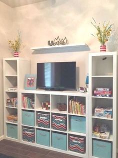 there is a television on top of the bookshelves in this room with blue bins