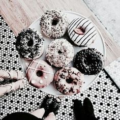 a white plate topped with lots of donuts on top of a wooden table next to a person