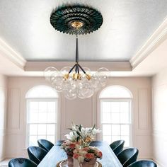 a dining room table with blue chairs and a chandelier hanging from the ceiling