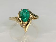 Pear Shaped Emerald Ring, Vintage Emerald Ring, Vintage Emerald Engagement Ring, Emerald Jewelry, Dainty Emerald Ring, Vintage Gemstone Ring A timeless and vibrant vintage emerald ring featuring a pear shaped center stone weighing 0.80 carats accented by a single diamond weighing 0.01 cts while set in solid 14k yellow gold. *Ring size: US 6 1/2 *Ring weight: 3.38 Grams *Center Stone dimensions: 8X6mm Fine Jewelry Bypass Ring With Center Stone, Fine Jewelry Pear-shaped Rings With Gemstone Accents, Pear-shaped Rings With Gemstone Accents, Pear-shaped Diamond Rings With Gemstone Accents, Fine Jewelry Pear-shaped Birthstone Ring With Accent Stones, Pear-shaped Emerald Ring With Accent Stones, Anime Rings, Ken And Dana Designs, Vintage Emerald Ring