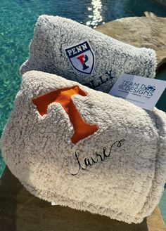 two towels sitting next to each other on the edge of a pool