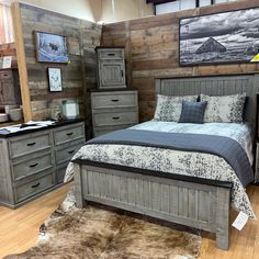 a bed room with a neatly made bed and dressers next to a wooden wall