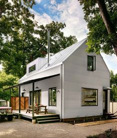 a small white house sitting in the middle of a forest