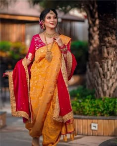 a woman in a yellow and red sari is walking down the street with her hand on