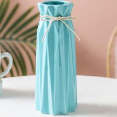 a blue vase sitting on top of a white table next to a cup and saucer