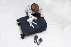 a small child sitting on top of a suitcase with a stuffed animal in front of it