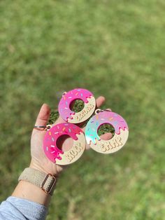 three donuts with sprinkles are held up in the air by someone's hand