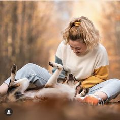 a woman is playing with her dog in the woods