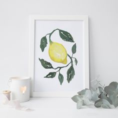 a lemon on a tree branch with leaves and a white cup next to the frame