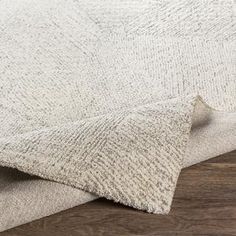 a close up view of a white rug on a wooden floor with wood grains