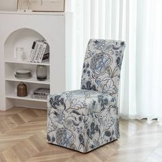 a blue and white chair sitting on top of a hard wood floor next to a book shelf