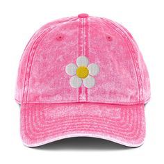 a pink hat with a white flower on the front and yellow center in the middle