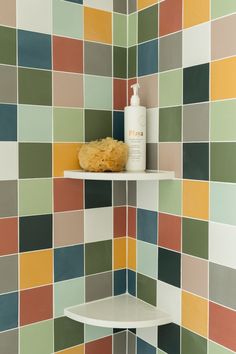 a bathroom with multicolored tiles on the wall and shelves in front of it