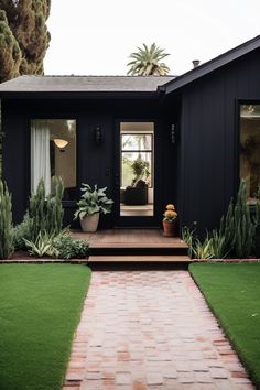 a black house with a brick walkway leading up to the front door and patio area