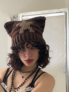 a woman wearing a knitted cat hat in front of a mirror with her hands on her hips