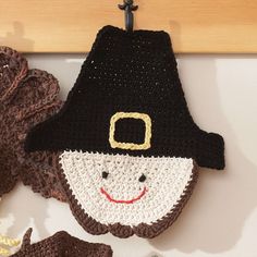 a crocheted hat with a smiling face on it and other items hanging from a hook