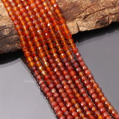 three strands of red glass beads sitting on top of a piece of wood