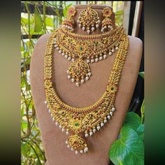 an elaborate necklace and earring set is displayed on a mannequin with leaves in the background