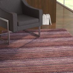 a chair sitting on top of a wooden floor next to a rug in front of a window