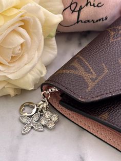 a purse with a key chain attached to it sitting next to flowers and a wallet