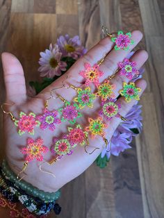 a person's hand holding several bracelets with flowers on them