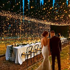 a couple standing next to each other in front of a long table covered with lights