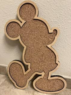 a wooden cutout of a mickey mouse sitting on the floor next to a wall