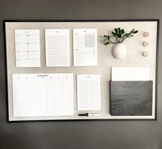 a wall mounted calendar, notepads and plant