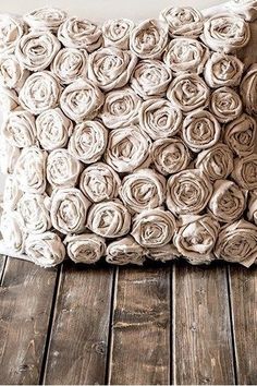 a pillow made out of rolled up fabric on top of a wooden floor in front of a white wall