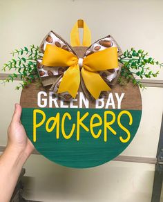 a wooden sign that says green bay packers with a bow on it's front