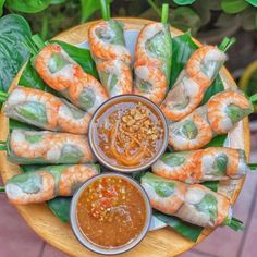 an overhead view of some food on a plate with dipping sauces and green leaves