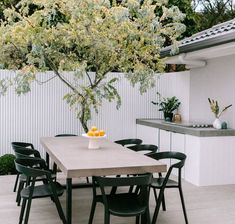 an outdoor table with chairs around it and a tree in the back ground behind it