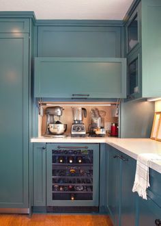 a kitchen with blue cabinets and white counter tops, an open wine cooler in the corner