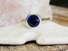 "This beautiful ring contains a 2.00 ct. lab created Blue Sapphire. The center stone measures 8mm. The ring is available in sterling silver, and 14k white or yellow gold. The mounting is a modern, high polish, heavyweight setting. This ring makes a great gift for a birthday, Mother's Day, bridesmaids, or any other special occasion. This ring could also be \"something blue\" for a wedding. Blue is the birthstone color for September. Please send me a message if you need a size not listed. *Matchin Blue Bezel Set Round Cut Birthstone Ring, Gift Sapphire Ring With Bezel Setting, Blue Birthstone Ring With Bezel Setting, Engagement Ring Bezel, Oval Sapphire Ring, Sapphire Solitaire Ring, Bezel Engagement Ring, Wedding Blue, Ring Sapphire