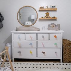 a baby's room with a dresser, mirror and stuffed animals on the drawers