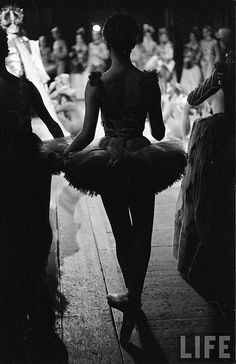 black and white photograph of two ballerinas walking down the street in front of an audience