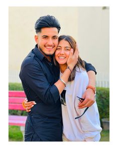 a man and woman hugging each other in front of a bench