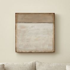 a painting hanging on the wall above a couch in a living room with white walls