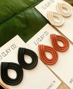 three pairs of earrings sitting on top of each other next to a green banana leaf