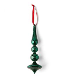 a green glass ornament hanging from a red ribbon on a white wall,