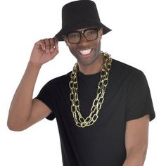 Jump-jump in with the original MCs and start a revolution with an Old School Rapper Costume Kit! Rapper Costume Kit features a large gold chain necklace large black rimmed glasses and a durable black stiff black hat. Hip hop and don't stop with our Rapper Costume Kit!Old School Rapper Costume Kit includes:Black hatBlack glassesChain necklace Decades Day Spirit Week Boys, Hiphop 90s Fashion, 80s Theme Party Outfit Men, Rapper Costume, Decades Costumes, Black Rimmed Glasses, Halloween Costume Black, Mexican Stuff, 80s Fashion Men