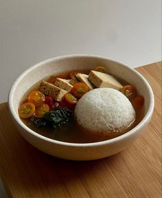 a bowl filled with rice and vegetables on top of a wooden table