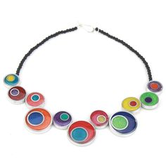 a multicolored necklace is hanging from a black cord and has five circles painted on it