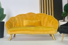 a yellow chair sitting on top of a white table next to a potted plant