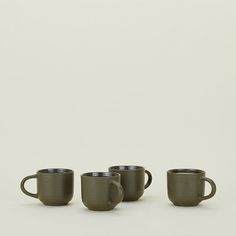 three coffee mugs sitting next to each other on a white surface with no one around them